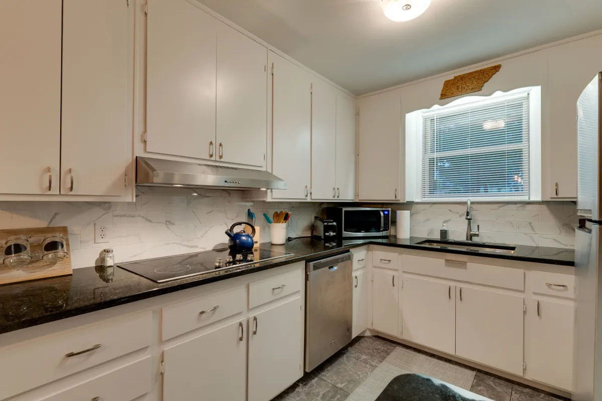 A modern kitchen with a granite countertop and stainless steel appliances, bathed in natural light from the window. The kitchen is spacious and inviting, perfect for prepping meals, hosting brunch, or sharing stories over dinner.