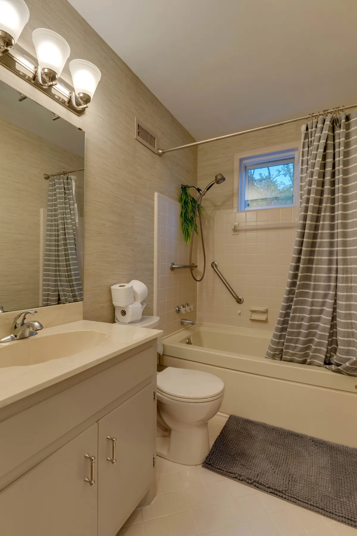 A tranquil bathroom with a vanity, bathtub, shower area, large mirror, and a window filling the space with natural light. The scene exudes a spa-like serenity, ideal for self-care and relaxation.