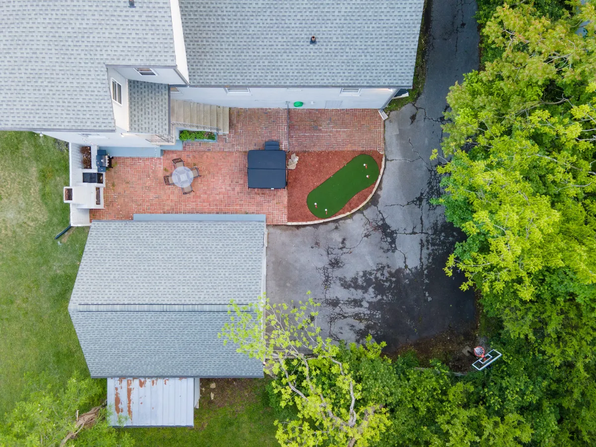 A welcoming patio area with lush green turf, comfortable seating, and mature trees providing shade. The putting green and outdoor setup are perfect for socializing, playing games, and family gatherings.